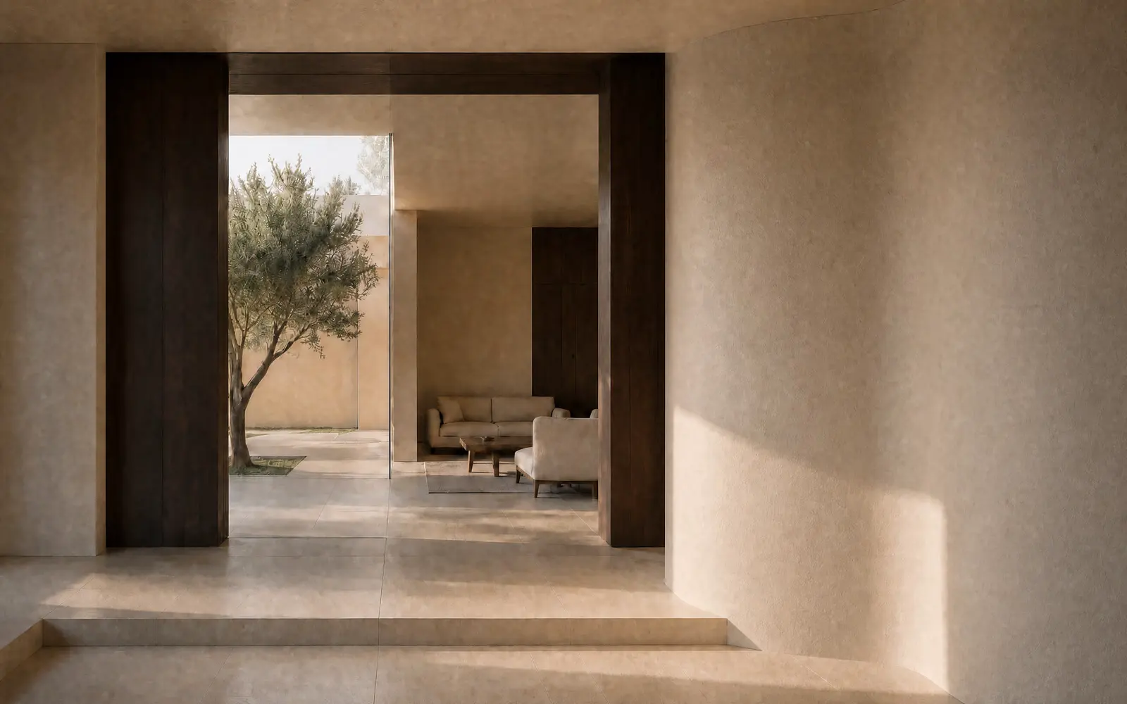 Morning light crosses a limestone threshold toward an olive tree and a quiet living room framed by dark timber and curved plaster.